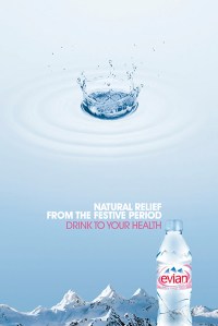 Bottle of Evian water with a mountain range background with a drop of water above.